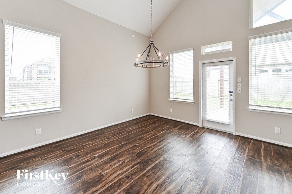 an empty living room with wood floors and a chandelier