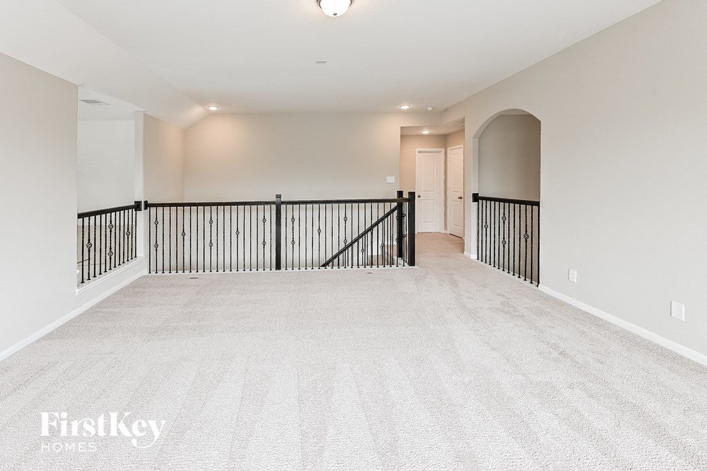 the upstairs loft is clean and empty with a guard rail and a door to the