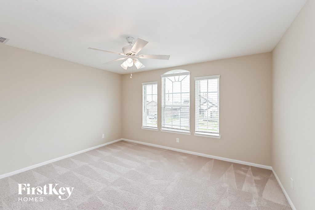 a spacious living room with windows and a ceiling fan