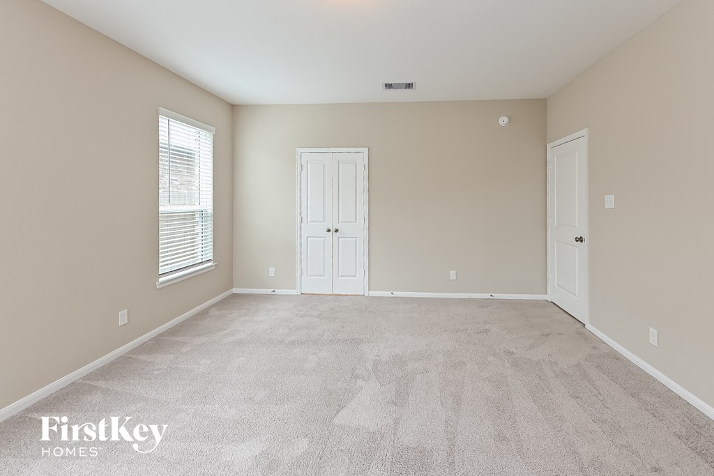 a spacious living room with carpeted floors and a white door