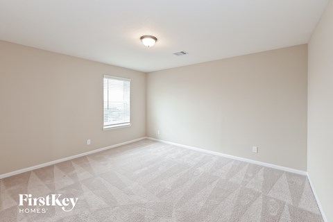 the spacious living room with white carpet and a window