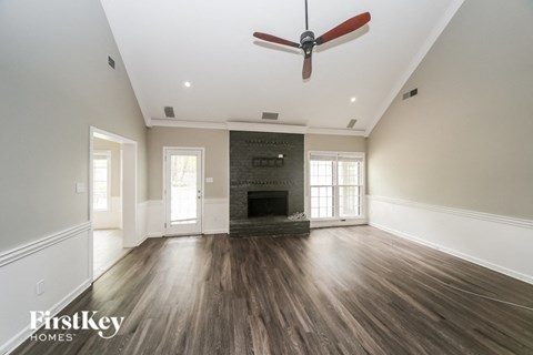 A spacious room with a fireplace and wood flooring.