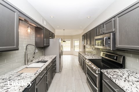 A modern kitchen with black cabinets and granite countertops.
