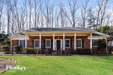 A brick house with a porch and a sign that says "FirstKey Homes".
