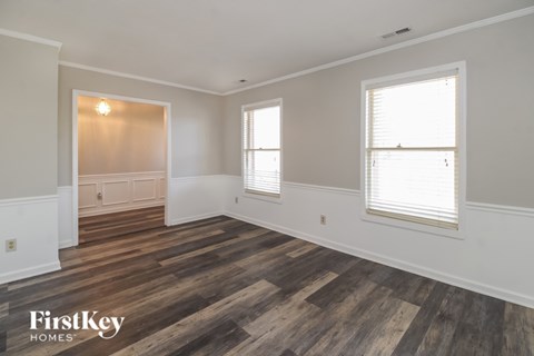 A room with wooden floors and two windows.