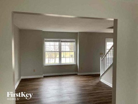 an empty living room with wood floors and a window