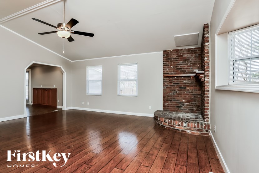 A room with a brick fireplace and wooden floors.