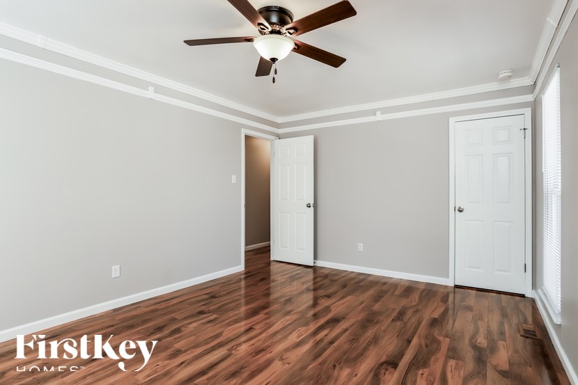 A room with a ceiling fan and wooden floors.