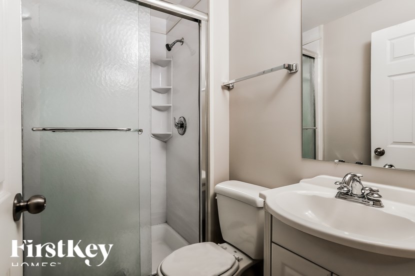A white bathroom with a toilet, sink, and shower.