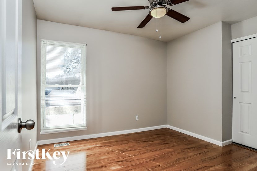 A room with a ceiling fan and a window with blinds.
