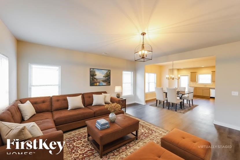 A living room with a brown leather couch and a chandelier.