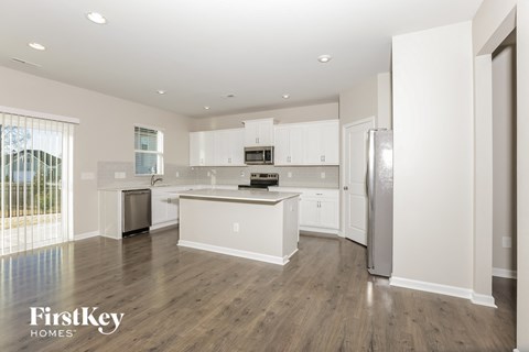 A kitchen with white cabinets and a wooden floor.
