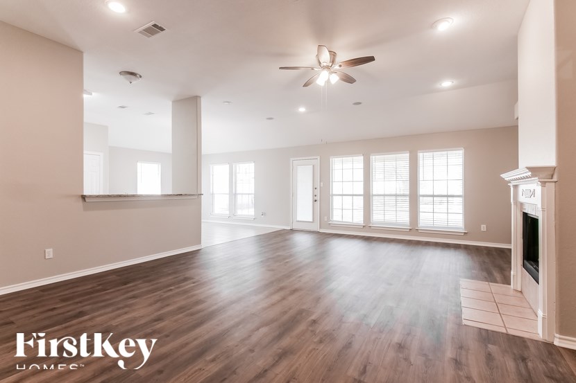 A spacious room with wooden floors and a fireplace.