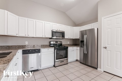 A kitchen with white cabinets and appliances.