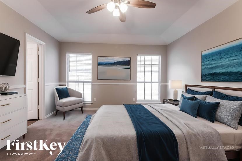 A bedroom with a large bed and a painting of the ocean on the wall.