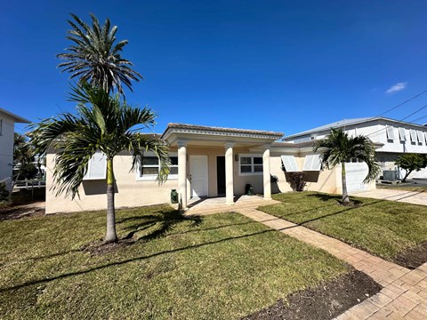 A house with a white exterior and a palm tree in front.