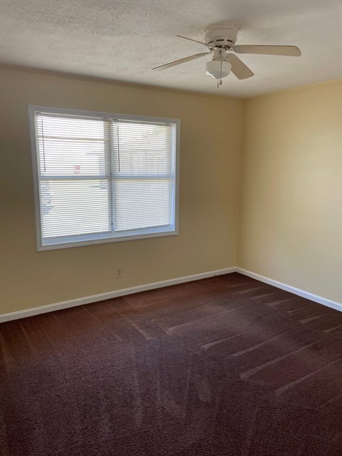 A room with a ceiling fan and a window with blinds.