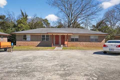 A house with a red door and a car parked in front.