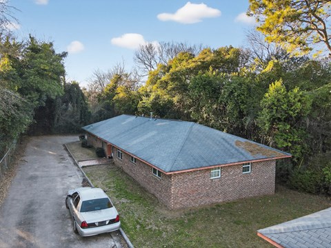 A car is parked in front of a house with a metal roof.