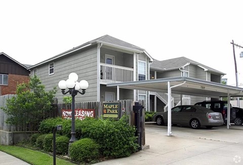 A two-story building with a balcony and a sign that says "Maple Park".