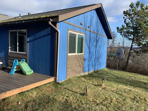 a blue house with a backyard with a play set