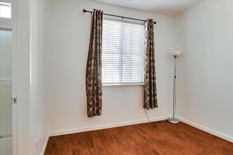 a living room with wood floors and a window with curtains
