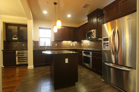 A modern kitchen with dark wood cabinets and stainless steel appliances.