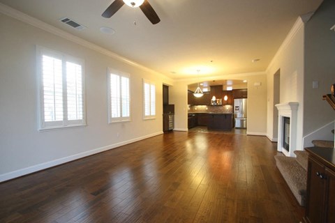 A spacious room with wooden floors and a ceiling fan.