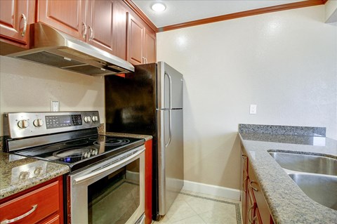 A kitchen with a stove top oven, refrigerator, and sink.