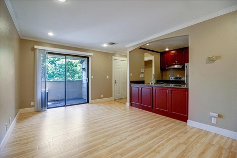 A spacious living room with a sliding glass door leading to a balcony.