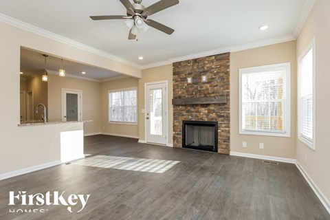 A spacious living room with a fireplace and a ceiling fan.