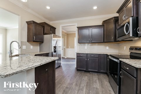A kitchen with dark brown cabinets and granite countertops.