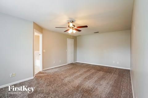 a spacious living room with carpet and a ceiling fan