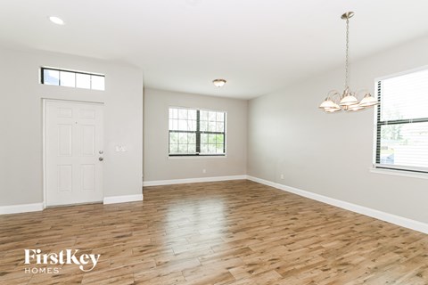A spacious room with wooden floors and a chandelier hanging from the ceiling.