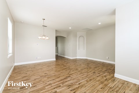 A large empty room with wooden floors and a chandelier.