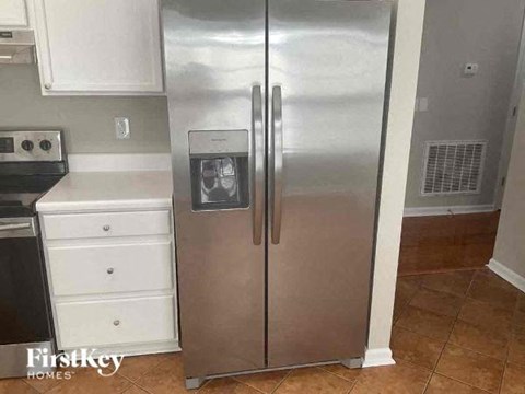 a stainless steel refrigerator in a kitchen with white cabinets