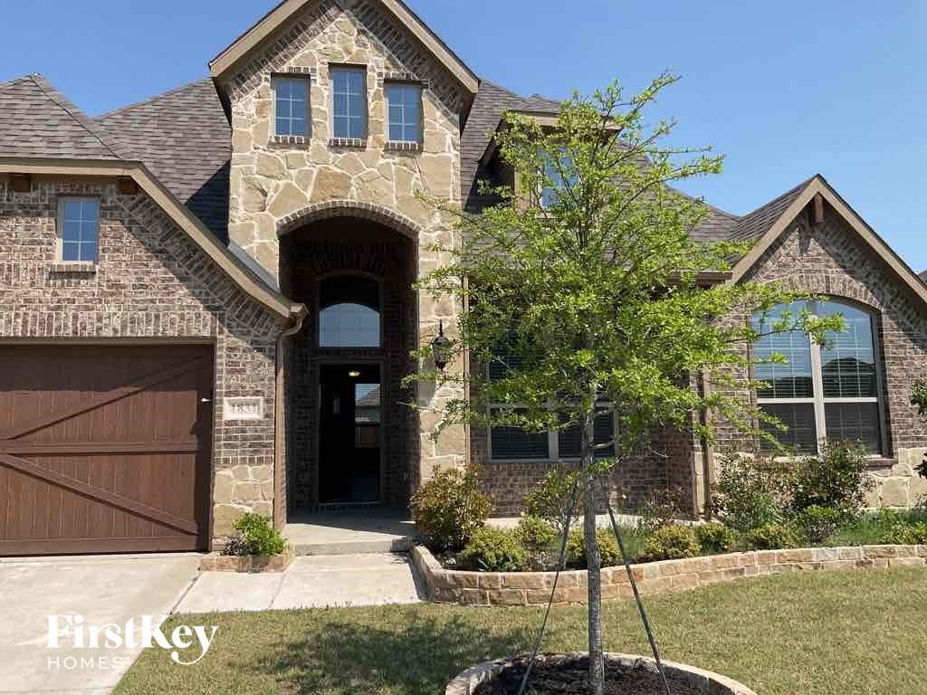 the front of a house with a tree in the front yard