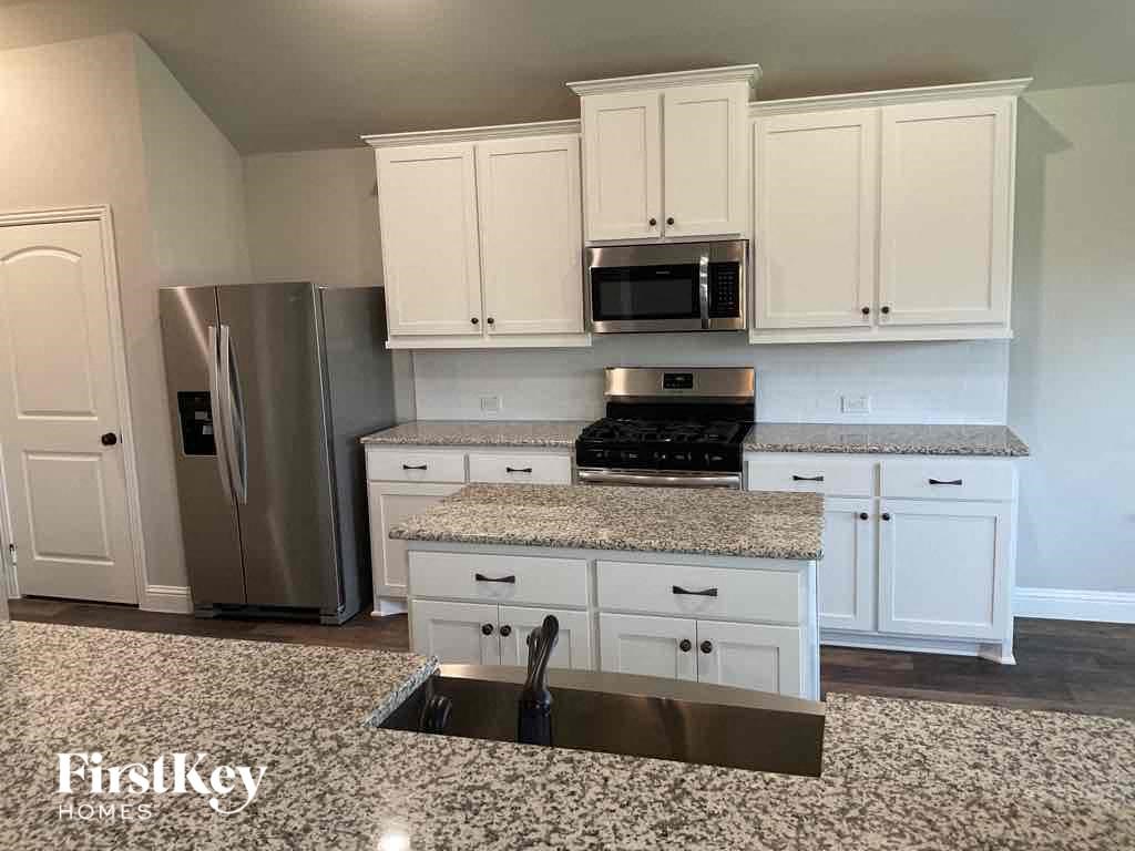 an updated kitchen with white cabinets and granite counter tops