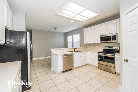 A kitchen with white cabinets and a black refrigerator.