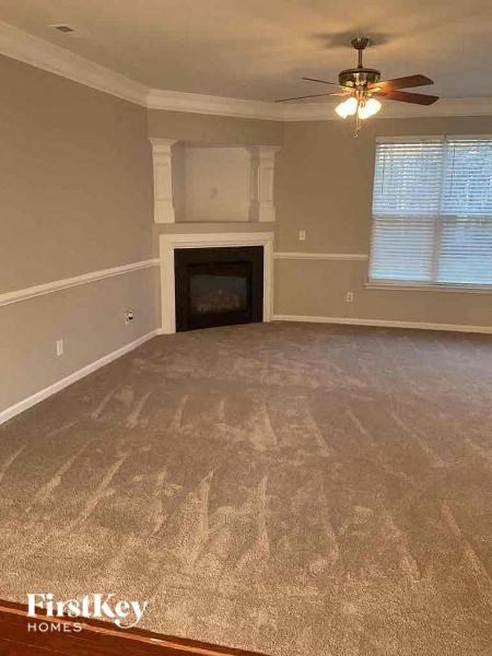 an empty living room with a ceiling fan and a fireplace