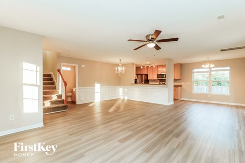 A spacious living room with wooden floors and a ceiling fan.