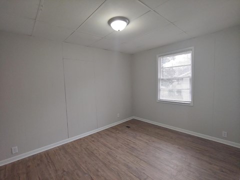 a living room with a wood floor and white walls and a window