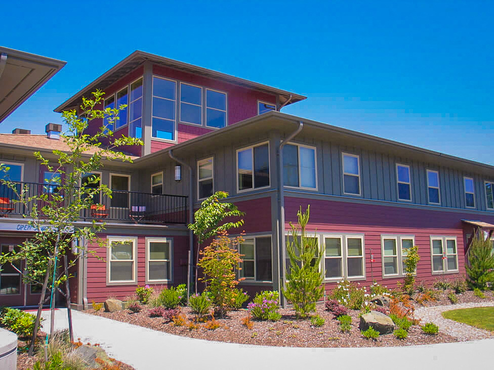 a red house with a driveway and landscaping in front of it