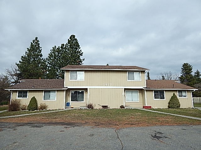 a beige house with a yard and trees