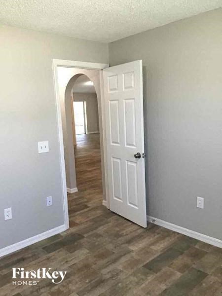 A room with a white door and a wooden floor.