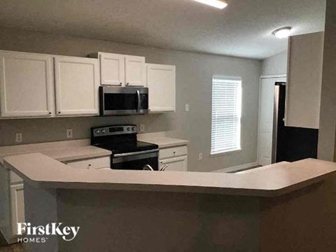 A kitchen with white cabinets and a FirstKey Homes logo.