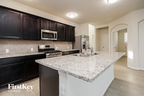 a kitchen with granite countertops and black cabinets and a sink