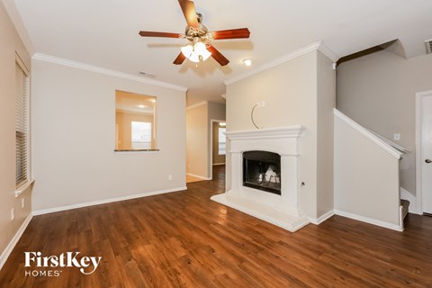 A spacious living room with a fireplace and a ceiling fan.