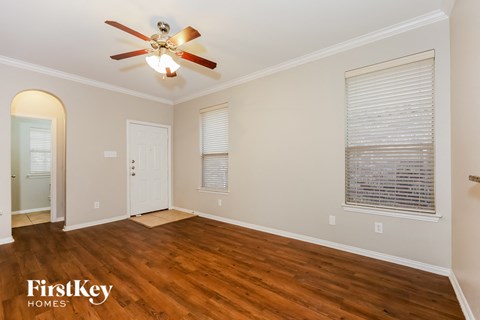 A room with a ceiling fan and wooden floors.
