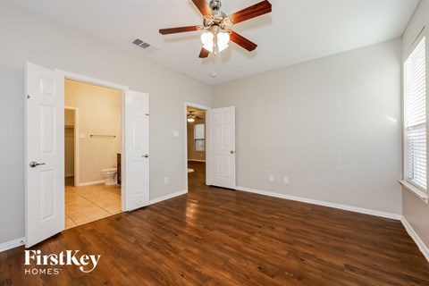 A spacious room with a ceiling fan and wooden flooring.